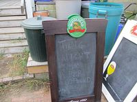 Full front view of one side of the wooden framed chalkboard sign with Moosehead logo plaque at top and some chalk writing visible on blackboard surface.