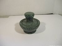 Marble pestle on top of mortar, showing full assembled set from angle.