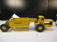 Full side view of the yellow Nylint Tournahopper toy truck showing condition and length.