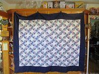 Full view of the quilt hanging, showing pattern and navy border.
