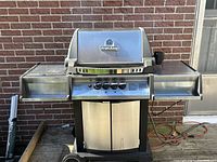 Front view of stainless steel gas grill with side shelves extended