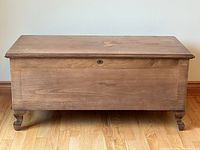 Closed chest, front view showing wood exterior, cabriole legs and lock escutcheon