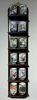 Full view of wooden display shelf holding 12 porcelain tea cups in a vertical arrangement.
