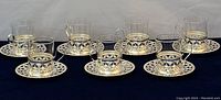 Full set of seven German teacups with silver-plated brass holders and matching saucers displayed on white background.