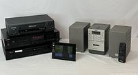 Photo showing all components together: Sony CD player CDP-490, Sylvania VHS VCR, Sony S-Frame digital photo frame, Sony PMC-D305 component system with separate speakers and remote, Denon DVD video player.