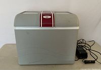 Closed view of Koolatron P95 electric travel cooler with 12 volt cord and AC adapter on side.
