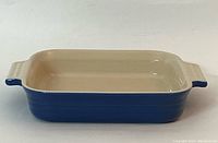 Front view of blue and beige square baking dish on white background, showing interior and handle details.