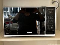 Front view of Panasonic The Genius microwave oven showing the closed door, digital display, and control panel.