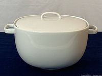 Front view of white porcelain covered soup tureen with lid and handles.