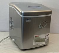 Front and side angle view of Salton IM-2022 portable ice maker in silver with control panel and power cord visible.