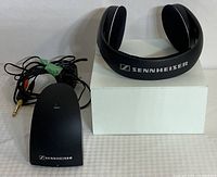 Photo of Sennheiser wireless transmitter with wired 3.5mm plug and the adjustable padded headband of the headphones with branding
