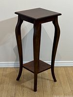 Full angled view of the small wooden side table showing curved legs and upper square top.