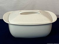Front angled view of the white covered dish showing overall shape and handles