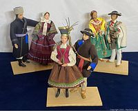 Overview image of all three pairs of Polish folk dolls on wooden bases showing traditional attire details
