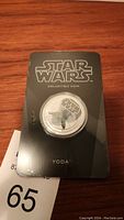 Front view of the 2011 Star Wars Yoda collectible coin in original black blister card packaging with Star Wars branding and Yoda text.
