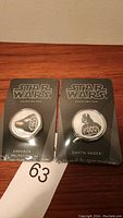 Two Star Wars collectible coins packaged on black card backings depicting Emperor Palpatine and Darth Vader.