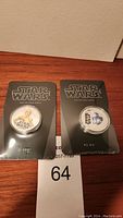 Two Star Wars collectible coins sealed in original black packaging showing C-3PO and R2-D2 characters.
