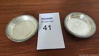 Two small round silver dishes placed next to a MaxSold lot number card, showing both dishes and their relative size.