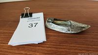 800 silver shoe-shaped ashtray on wooden surface, angle showing profile and texture