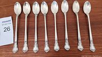 Eight Gorham sterling silver iced tea spoons displayed top view on wood surface