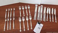 Full set of 24 pieces arranged on table, including 16 forks and 8 knives with binder clip tag