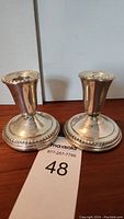 Two sterling silver candle holders showing a weighted round base and slightly flared top