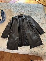 Full view of black Danier leather jacket laid flat showing front and inside quilted lining.