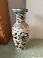 Front view of tall ceramic floor vase showing detailed peacock and floral motifs with wide neck and decorative band.