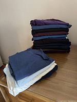 Two separate photos showing stacks of folded pants and shorts in various colors on a wooden surface.