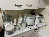 Full view of the lot on kitchen counter showing all appliances: food processor, hand mixer, chopper, grinder, slow cooker, kettle, toaster
