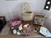 Wide view of sewing and knitting supplies including wicker basket, yarns, crochet pieces, and fabric rack.