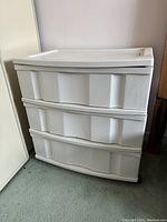 Front view of white plastic three drawer storage tote showing all drawers and overall condition with visible minor dirt and scuffing.
