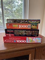 Stack of 5 puzzles viewed from the side showing the titles, brands, and piece counts.