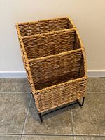 Front view of the woven rattan and metal magazine rack showing three compartments and overall structure