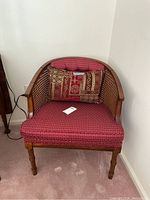 Front view of wooden caneback chair with red fabric seat and matching pillows