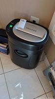 Full view of the black and silver Royal 1212X paper shredder showing overall design and size relative to surrounding objects.