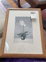 Full view of the framed artwork showing the wooden frame, matting, and the orchid print inside.