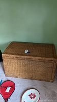 Full view of the large rectangular wicker trunk placed on carpet.