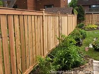 Residential wooden privacy fence installation example, vertical cedar panels with posts and landscaped yard