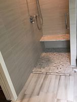 Shower with large-format beige wall tile, mosaic floor tile and built-in bench