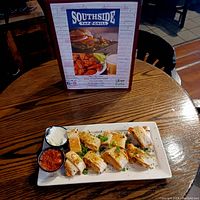 Gift card promotional display with an appetizer plate featuring chicken bites and dipping sauces on a wooden table.