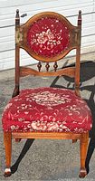 Front view of vintage hardwood chair with floral red upholstery and carved details