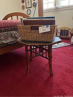 Bamboo octagonal end table with woven basket and books placed on red carpet in a room with natural light.