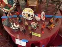 Wide view of the chicken decor collection showing multiple chicken and rooster figurines in various sizes and styles, arranged on a table with red tablecloth