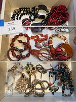 Overall overview of three-row jewelry tray containing assorted necklaces, bracelets, bangles, earrings and brooch