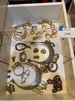 Top-down view of various gold plated and silver-tone necklaces, earrings and bracelets displayed in a drawer.