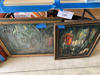 Two paintings side by side on floor with blue tape size labels