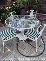 Full view of round glass-topped table with four striped-cushioned chairs arranged around it