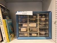 Blue display case with semi-precious gems and minerals in clear compartments, each labeled by name