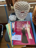 Photo of Princess Diana and Bill Clinton paper doll books stacked beside a crystal ice bucket and a cut crystal music box.